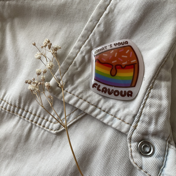 What's Your Flavour cake Pride badge on a denim jacket with baby's breath flowers